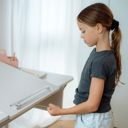 moll Champion Desk - Center Up being used by a little girl who is pulling on the pulley system to elevate the angle of the work surface.